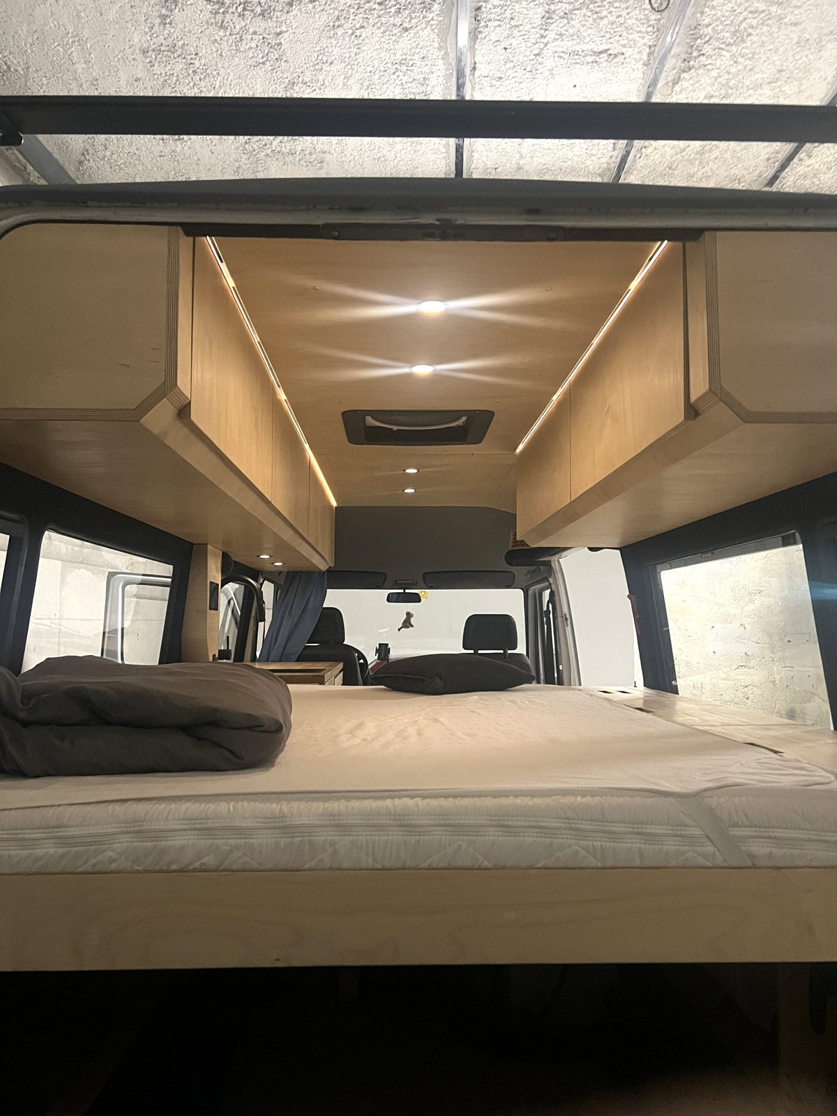 Van-Ausbau aus Birkensperrholz mit Bett, Oberschränken und Lichtleisten