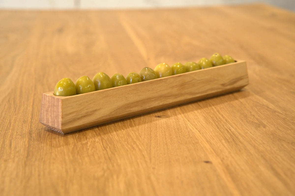 Olivenschale aus Esche mit grünen Oliven in einer Reihe